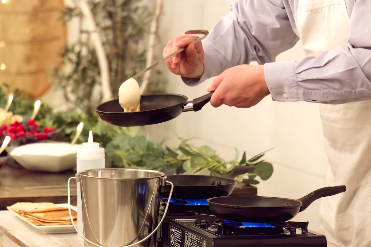 a man pouring crepe batter into a pan